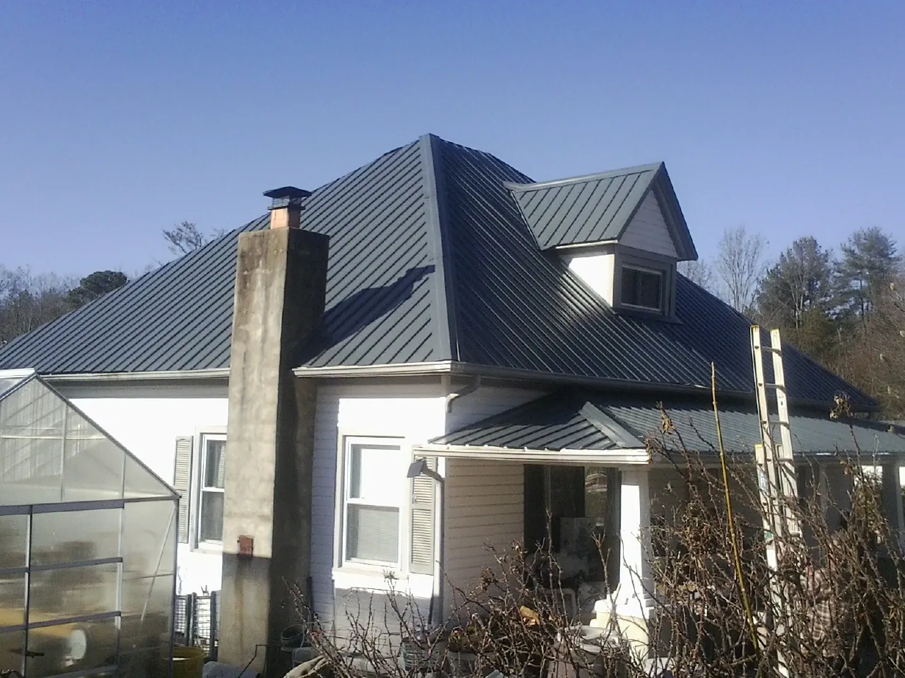 Dark blue standing seam metal roof on a white farmhouse with dormer — Slate & Tile Roof Repair by Roofing Brothers in Greencastle