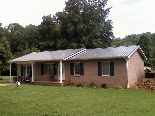 Gray metal roof on a brick ranch house with a side carport in Greencastle