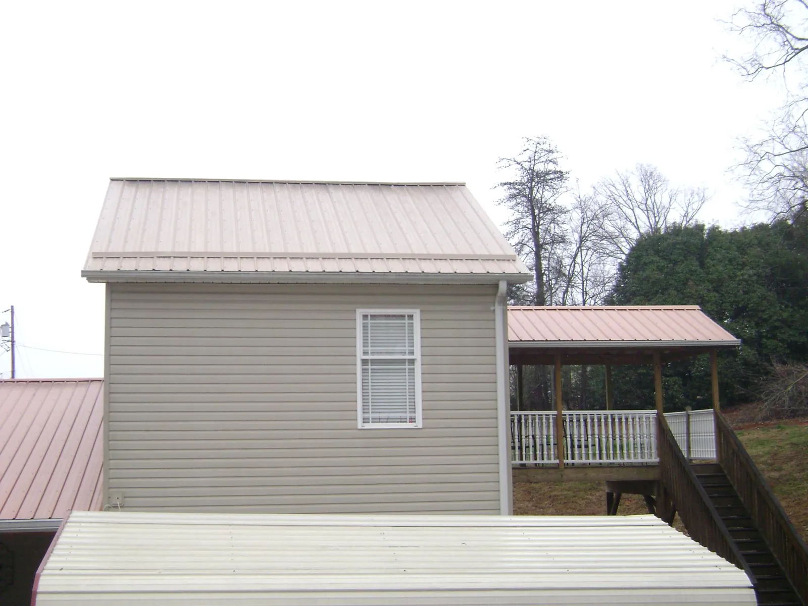 Tan metal roofs on a two story addition and attached porch, from a Roof Replacement job in Greencastle