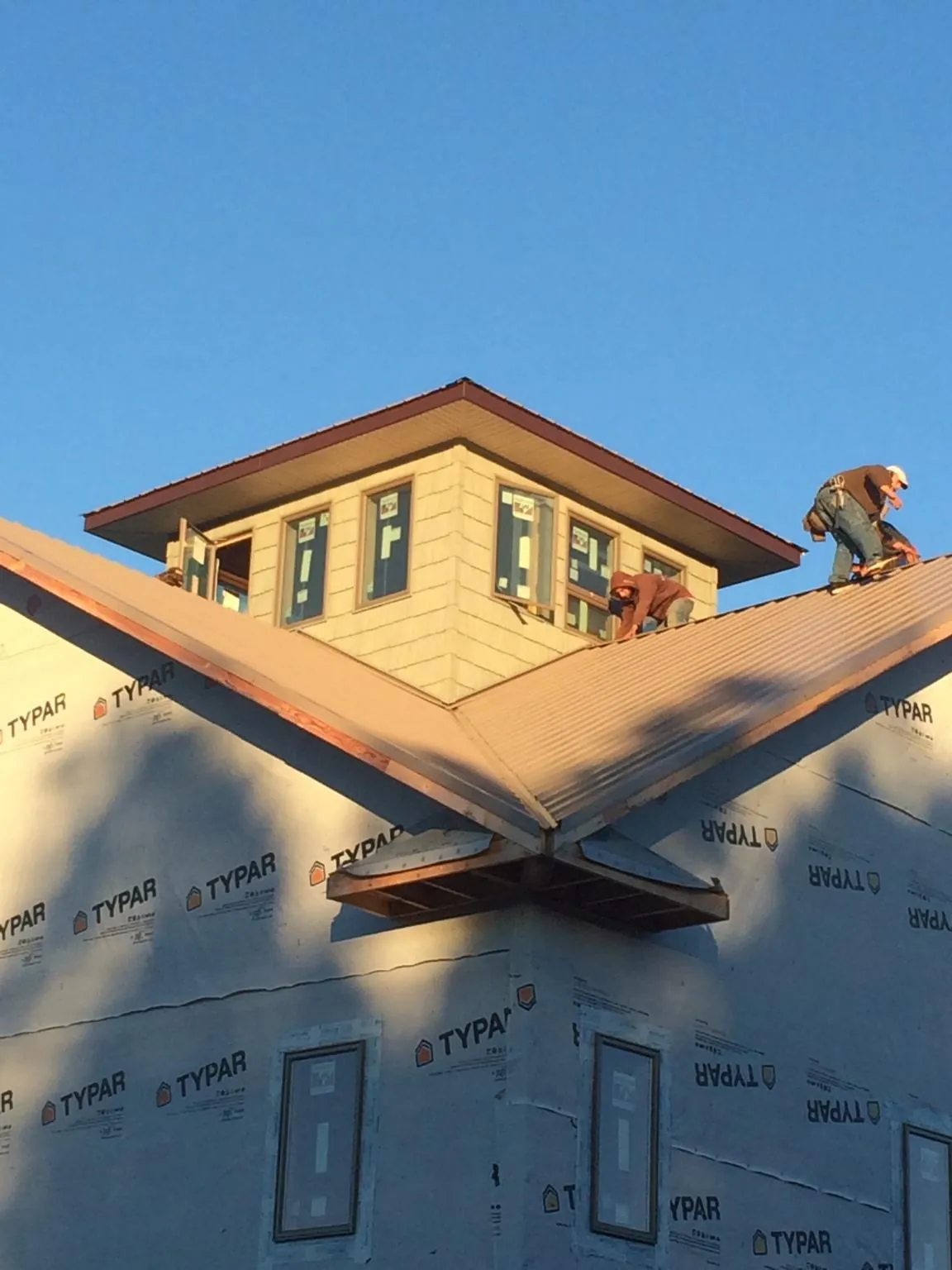 Roofers working around a rooftop cupola on a new metal roof at sunset — Roof Waterproofing in Greencastle by Roofing Brothers